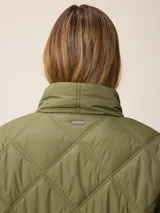 Campera larga acolchada con diseño de rombos, cierre frontal completo y cuello alto. Presenta puños elásticos y un pequeño logo aplicado en el pecho.