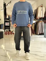 Sweater de punto color beige con cuello redondo, manga larga y diseño estampado en el pecho con las frases "TOP STYLE" y "follow your dreams" en color marrón.