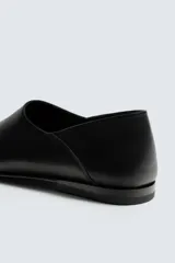 Mocasín de piel color negro, con diseño minimalista de parte superior lisa, horma ligeramente cuadrada y suela ultrafina.