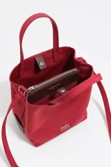 Bolso de mano pequeño tipo tote bag, color rojo, confeccionado en gabardina con detalles en piel. Posee asas de mano y correa ajustable para llevar al hombro o cruzado. Lleva placa metálica con el logo de la marca en el frente.