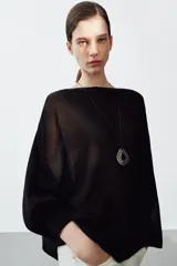 Jersey de punto con diseño tipo capa asimétrica, cuello redondo y mangas largas con puños ajustados.