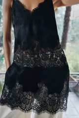 Top largo confeccionado en tejido de encaje con escote en pico y tirantes finos. Presenta una combinación de tejidos a tono con diseño sofisticado.