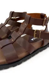 Sandalias de cuero marrón con tiras horizontales y ajuste con hebilla al tobillo.