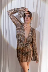 Vestido corto confeccionado en tul y lycra con estampado animal print de serpiente, escote en V pronunciado y mangas largas con diseño acampanado.