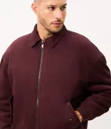 Campera bomber Marfinno para hombre, de gamuza sintética (suede) color tostado, con cuello camisero, cierre frontal metálico, bolsillos frontales y terminaciones en rib en puños y ruedo.