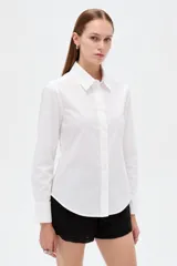Camisa de algodón blanca, de corte entallado al cuerpo, con cuello camisero, manga larga y cierre frontal de botones.