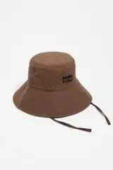 Gorro tipo bucket color marrón, confeccionado en algodón, con logo de la marca bordado en negro y cordones laterales ajustables.