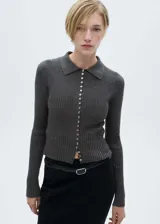 Buzo de punto fino en color gris oscuro, con diseño entallado, cuello camisero y cierre frontal completo con botones pequeños. Presenta textura acanalada y mangas largas.