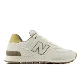 Championes urbanos New Balance modelo 574, en tonos beige y crema con detalles en amarillo mostaza en el talón y suela de goma color caramelo. Presentan el logo N característico en los laterales y tecnología de amortiguación ENCAP en la entresuela.