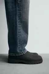 Bota tipo Chelsea de piel con acabado mate, diseño de horma redonda, elásticos laterales y suela track con volumen.