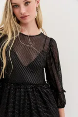 Vestido largo de tul negro con bordados de lentejuelas y canutillos, mangas tres cuartos abullonadas, cintura fruncida y falda con volado en el ruedo.