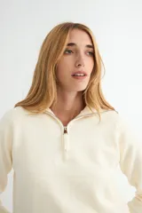 Buzo de punto gris con cuello polo y cierre frontal parcial, de manga larga y diseño holgado con puños y ruedo acanalados.