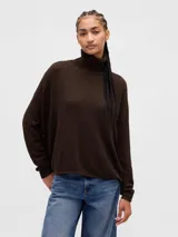 Buzo de punto con cuello alto, diseño de tejido pointelle con pequeños calados, mangas largas y corte holgado.