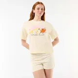 Pijama de dos piezas color amarillo, compuesto por una remera de manga corta con estampa frontal de Simba, Timón y Pumba bajo un arcoíris y la frase "Explore the wild", y un short a rayas sutiles con elástico en la cintura.