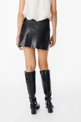 Mini falda tipo cruzada confeccionada en cuero, con detalle de cintura con tachas metálicas.