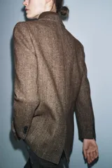 Blazer de Zara confeccionado en hilatura con lana, con diseño de espiga en tonos marrones. Presenta cuello solapa, manga larga con botones, bolsillo de vivo en el pecho y bolsillos delanteros con solapa. Cierre frontal con botones y forro interior negro.