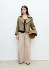 Chaqueta corta de estilo trench con cuello de solapa y cierre frontal de doble botonadura. Presenta diseño recto, manga larga y bolsillos laterales, confeccionada en tejido de mezcla de algodón con forro interior.