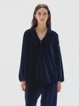 Camisa de terciopelo azul marino con cuello solapa, escote en V y mangas largas con puños elásticos. Presenta un diseño de silueta relajada y fluida.