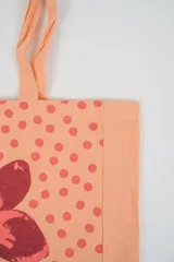 Bolso tote de tela con estampado de rayas verticales rosadas y blancas, laterales y asas en color beige. Presenta la palabra "BONJOUR" en verde en el centro y "INDIAN" en la parte inferior.
