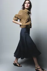 Falda midi de tiro alto con corte evasé y caída fluida. Presenta un diseño minimalista en color azul denim con cierre lateral oculto.
