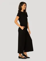 Conjunto de dos piezas compuesto por una remera de manga corta con cuello redondo y frunces laterales ajustables, y un pantalón de corte ancho con cintura elástica y bolsillos laterales.