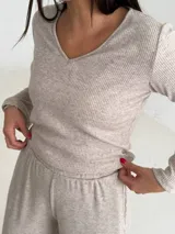 Remera de lanilla con textura acanalada, escote en V y mangas largas con terminación oxford. Presenta un diseño minimalista y cómodo.