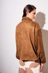 Sobrecamisa marrón de gamuza sintética, con cuello camisero, cierre frontal con botones, mangas largas con puños abotonados y bolsillos de parche en el pecho.