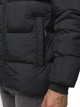 Campera puffer color verde militar, con diseño capitoneado, cuello alto y capucha integrada. Cuenta con cierre frontal, bolsillos laterales con cierre y puños con ojal para el pulgar.