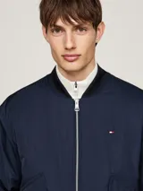 Campera bomber azul marino Tommy Hilfiger, con cuello, puños y bajo de punto canalé. Cierre frontal con cremallera, dos bolsillos laterales con botón a presión y logo bordado en el pecho.