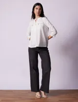 Blusa azul con cuello a la base y escote en V. Tiene bolsillos con cierre metálico.