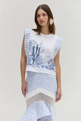 Remera blanca sin mangas con bordado y estampado de corales en tonos azules, con hombreras estructuradas decoradas con rayas celestes y blancas.