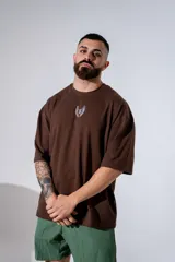 Remera oversize de algodón elastizado color marrón, con corte holgado y diseño de alas pequeñas estampado en el centro del pecho.