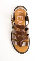 Sandalias cangrejeras de cuero marrón charol, estilo romano con múltiples tiras cruzadas, suela track plana y cierre de hebilla metálica ajustable en el tobillo.