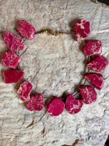 Collar corto elaborado artesanalmente con piedras naturales de jaspe en tonos fucsia y frambuesa con vetas beige, intercaladas con cuentas metálicas y cierre de mosquetón dorado.
