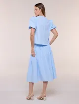 Blusa celeste a rayas blancas de calce recto con textura gofrada, cuello redondo con escote en V y mangas cortas abullonadas con elástico en los puños.