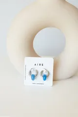 Aros de argolla en acero quirúrgico con dije de piedra natural en tono azul.
