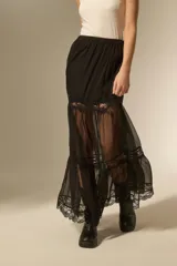 Falda larga de color negro, confeccionada en tela semitransparente con detalles de encaje en los niveles de la falda y cintura elástica.