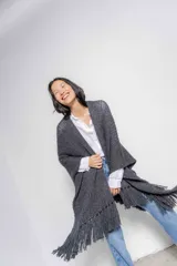 Ruana de tejido de punto grueso color gris con flecos en el ruedo.