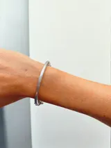 Pulsera rígida plateada con dijes colgantes y cuentas decorativas. Incluye cuentas de cristal facetado, cuentas de cerámica con estampado floral, cuentas de piedra veteada y dijes metálicos con forma de corazón, hoja y gota.