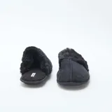 Pantuflas tipo mule de color negro, confeccionadas en material aterciopelado con detalle de borde en pelo sintético. Poseen suela plana y diseño abierto en el talón.