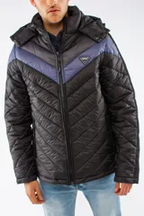 Campera puffer de nylon con relleno de guata, diseño capitoneado y capucha desmontable. Presenta un patrón de chevron en color azul sobre base negra, cierre frontal y bolsillos laterales con cierre.