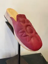 Mules de cuero color rojo con diseño de sol bordado.