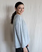 Remera de manga larga confeccionada en lanilla gris melange, con diseño holgado y escote redondo fruncido.