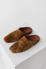 Zueco tipo mule de pelo natural en color camel, con plantilla de cuero y punta cuadrada.