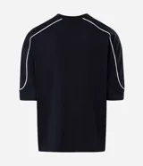 Remera de algodón color blanco, con cuello redondo, manga corta y detalle de raya negra contrastante que recorre la parte superior de los hombros y mangas. Diseño de corte holgado.