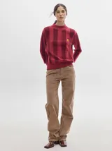 Pantalón de pana roja con corte holgado y tiro medio. Presenta una línea dorada a lo largo de la pierna.