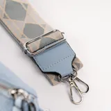 Riñonera celeste de cuero sintético con cierre plateado, correa de tela estampada y monedero redondo con cierre.