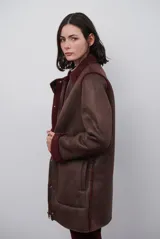 Chaquetón de efecto cuero en color marrón, con interior y detalles en corderito color bordó. Presenta cierre frontal con cremallera y botones a presión, cuello solapa y mangas largas con puños de corderito.