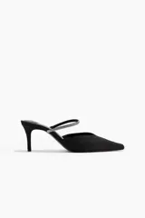 Sandalias tipo mule de tela negra con punta fina y taco fino forrado. Presenta una tira fina en el empeine decorada con strass y elástico lateral para mayor ajuste.