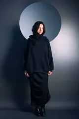 Buzo negro de corte oversize con cuello alto tipo polera y capucha integrada. Presenta mangas largas con puños ajustados y un diseño holgado en el cuerpo.
